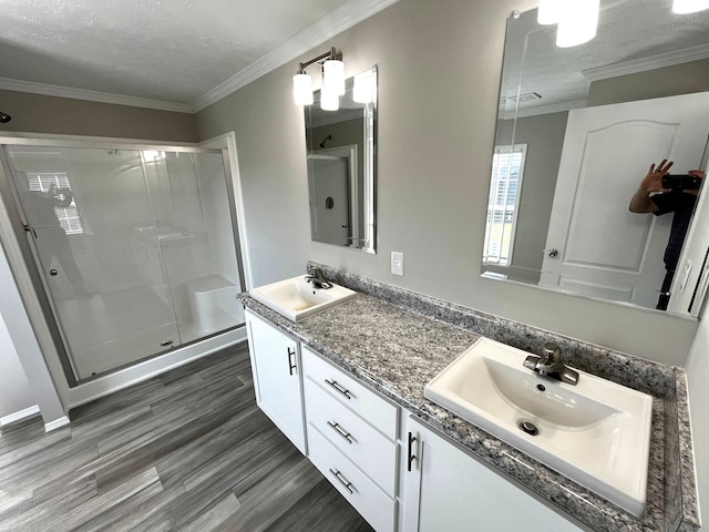 bathroom with a sink, wood finished floors, a stall shower, and crown molding