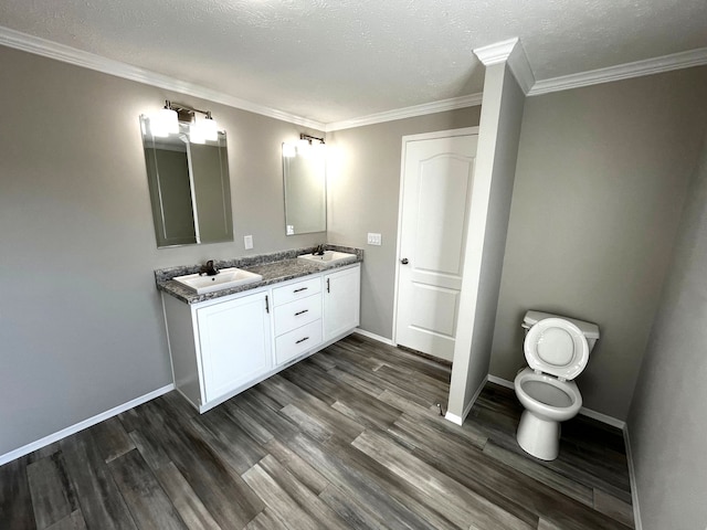 bathroom featuring wood finished floors, crown molding, baseboards, and a sink