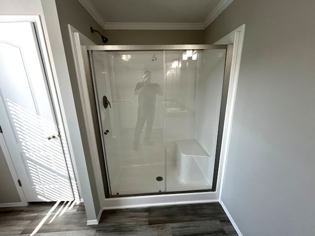 bathroom with baseboards, wood finished floors, a stall shower, and ornamental molding