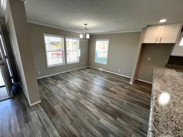 unfurnished dining area featuring an inviting chandelier, dark wood-type flooring, crown molding, and a textured ceiling