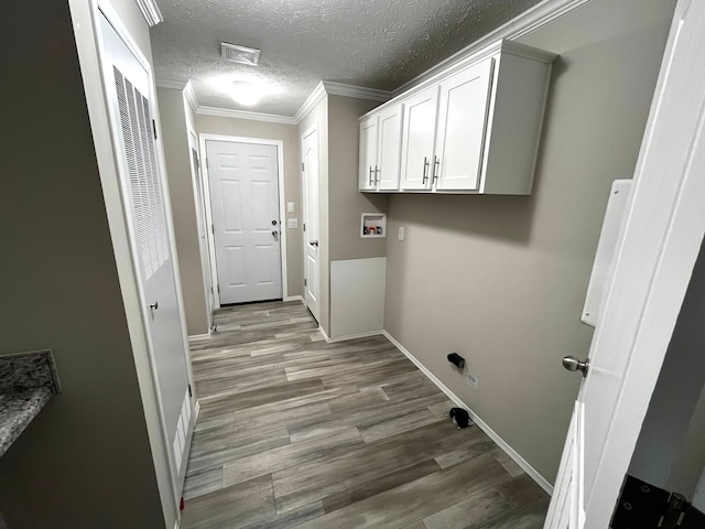 clothes washing area featuring crown molding, baseboards, hookup for a washing machine, wood finished floors, and a textured ceiling