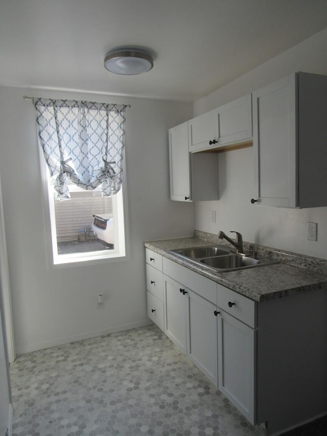 kitchen with white cabinets, baseboards, and a sink