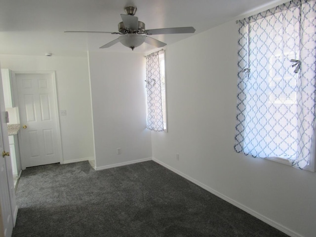 unfurnished room featuring baseboards, a ceiling fan, and dark carpet