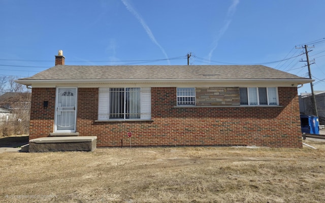 bungalow-style home featuring brick siding, roof with shingles, and a chimney