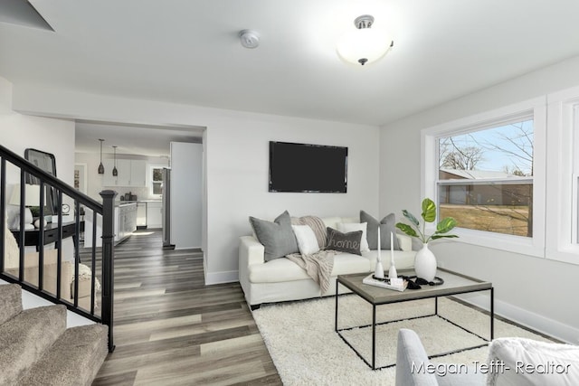 living area with stairway, baseboards, and wood finished floors