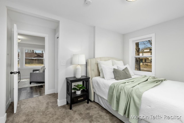 carpeted bedroom featuring multiple windows and baseboards