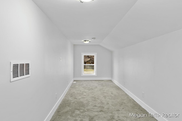 interior space with visible vents, carpet floors, baseboards, and vaulted ceiling