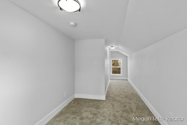 corridor with vaulted ceiling, baseboards, and carpet floors