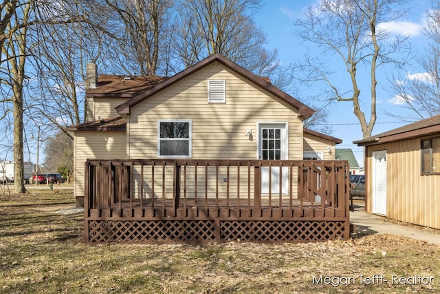 back of house with a chimney and a wooden deck