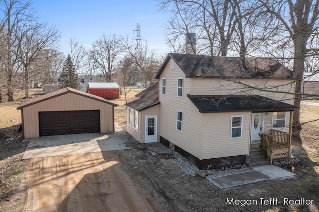 view of side of property featuring an outbuilding, a shingled roof, and a detached garage