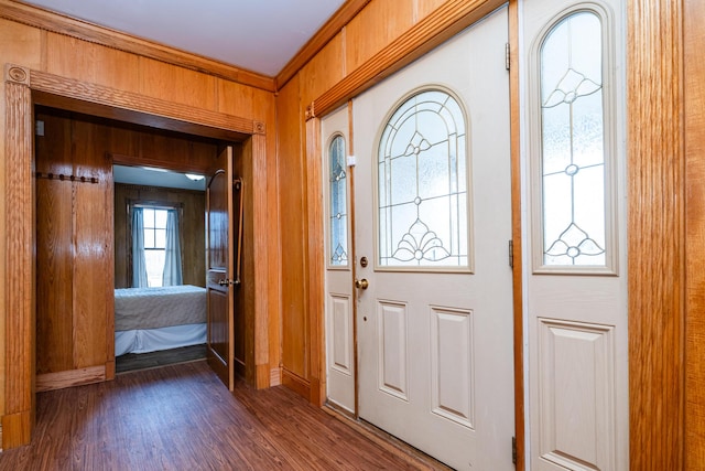 entryway featuring dark wood-style floors, wooden walls, and ornamental molding