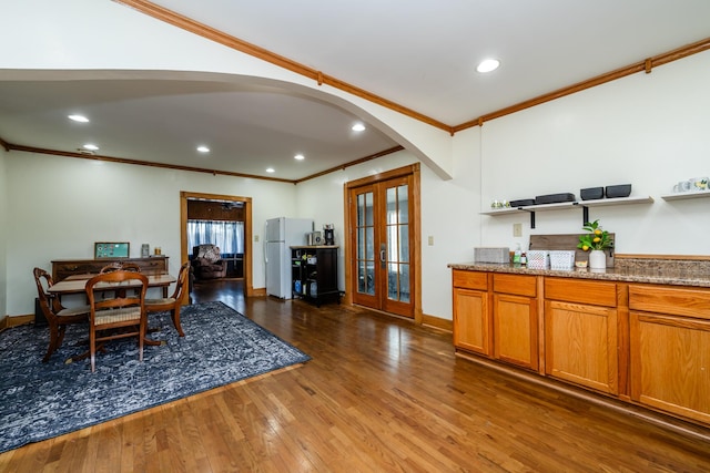 dining room with wood finished floors, french doors, arched walkways, and baseboards