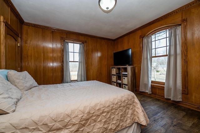 bedroom with wood walls, dark wood-type flooring, and ornamental molding