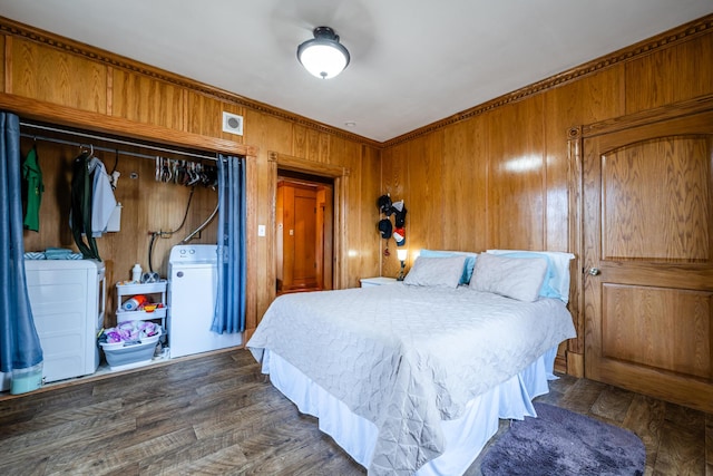 bedroom with dark wood-style floors, wooden walls, washer and dryer, and a closet