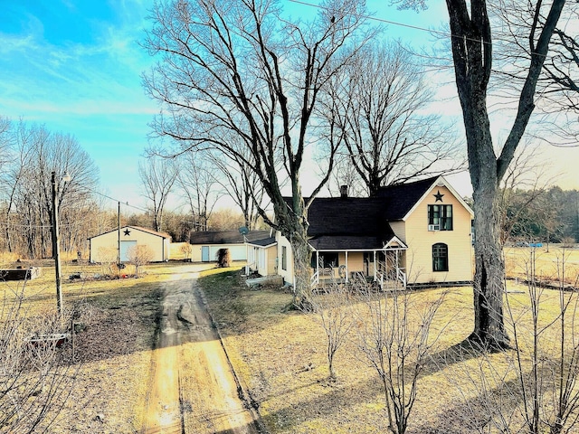 view of front of house featuring a porch, an outbuilding, and driveway