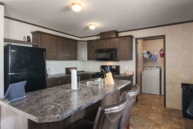 kitchen featuring black appliances, a breakfast bar, dark countertops, washer / dryer, and dark brown cabinets