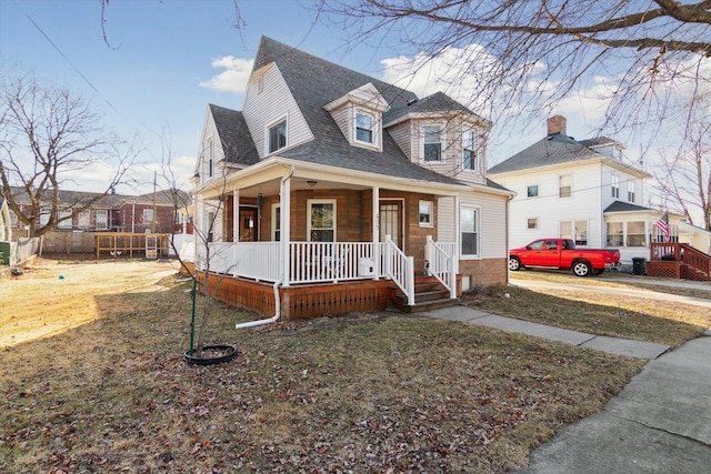 view of front of property with a porch, fence, and roof with shingles