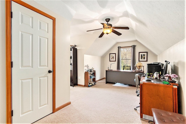 office area with baseboards, vaulted ceiling, light carpet, a textured ceiling, and a ceiling fan