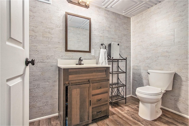 half bathroom with baseboards, toilet, wood finished floors, and vanity