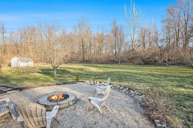 view of yard with an outbuilding, a storage unit, and a fire pit