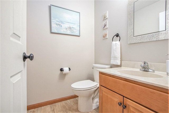 half bath featuring vanity, toilet, and baseboards