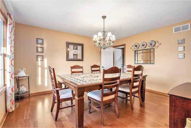 dining space with an inviting chandelier, baseboards, visible vents, and light wood-type flooring