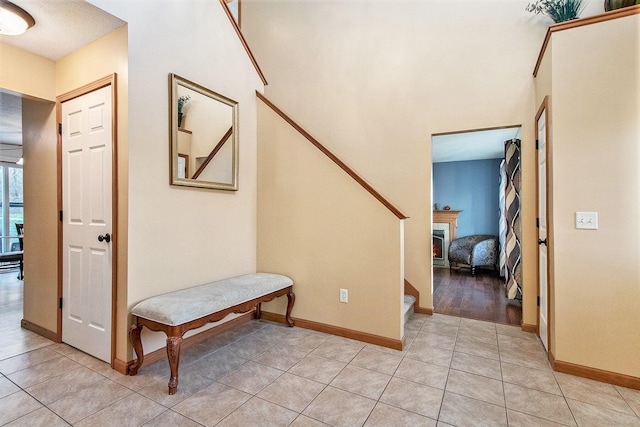 corridor featuring light tile patterned floors, stairs, and baseboards