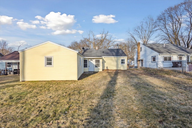 back of property featuring a chimney, a yard, and fence