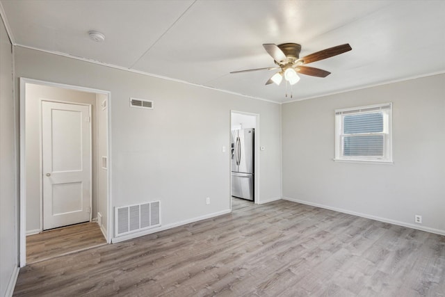 unfurnished room featuring visible vents, crown molding, a ceiling fan, and wood finished floors