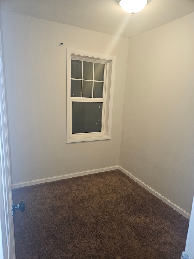 empty room with baseboards and dark colored carpet