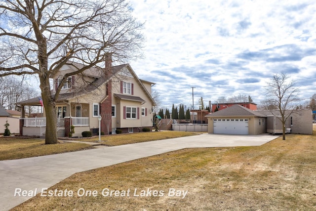 view of front of house with driveway, a front lawn, a porch, an outdoor structure, and a chimney