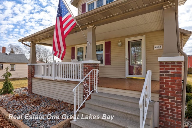 doorway to property featuring brick siding and covered porch