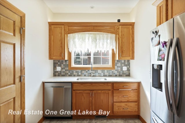 kitchen featuring light countertops, tasteful backsplash, appliances with stainless steel finishes, and a sink