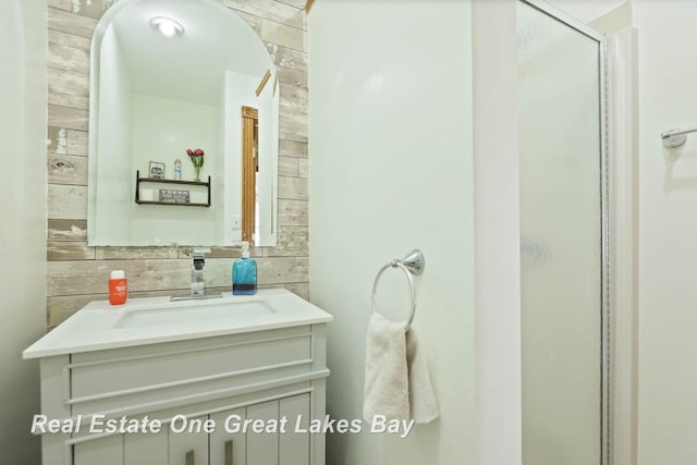 bathroom featuring vanity, a stall shower, and wood walls