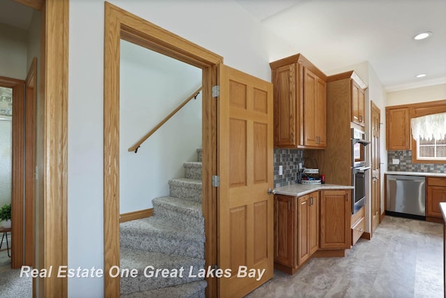 kitchen featuring backsplash, recessed lighting, stainless steel appliances, brown cabinetry, and light countertops