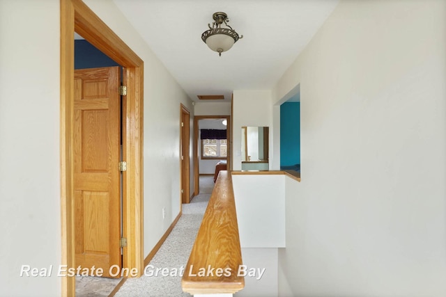 hall featuring an upstairs landing, baseboards, and carpet