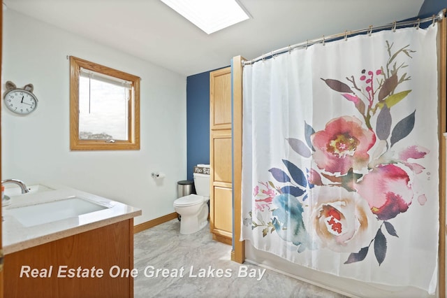 bathroom featuring toilet, a skylight, vanity, and a shower with curtain