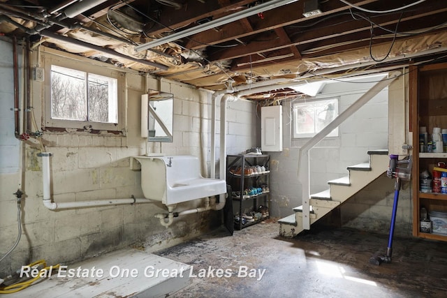 below grade area featuring stairs, electric panel, plenty of natural light, and a sink