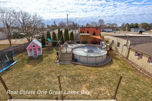 view of yard featuring a fenced in pool, a playground, a trampoline, and fence