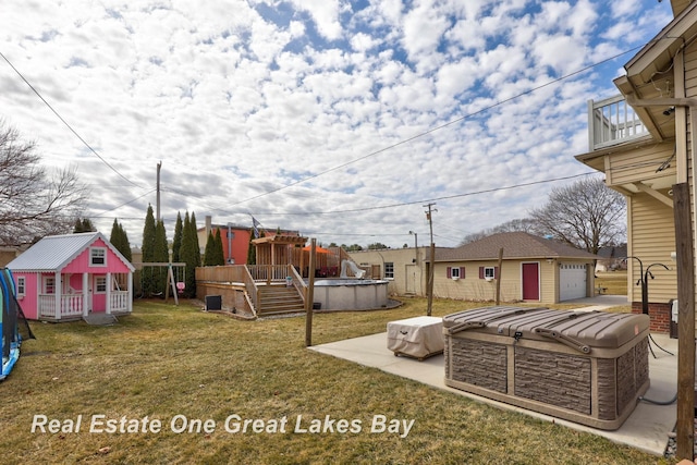 view of yard featuring an outdoor pool, a detached garage, a balcony, and an outdoor structure