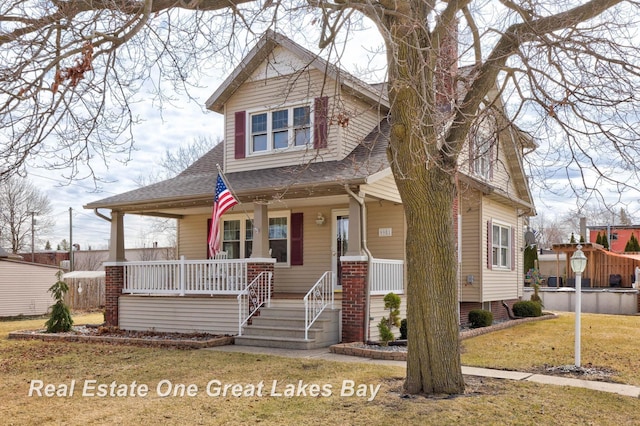 view of front facade featuring a porch, a shingled roof, and a front lawn