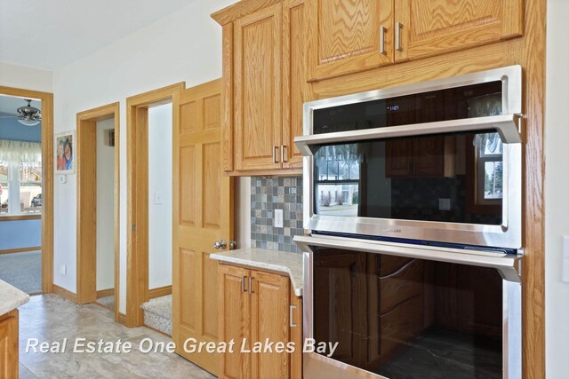 kitchen with decorative backsplash, double oven, baseboards, and ceiling fan