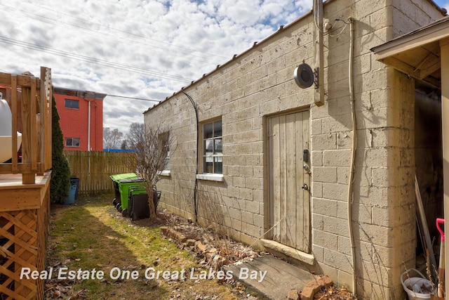 view of home's exterior featuring concrete block siding and fence