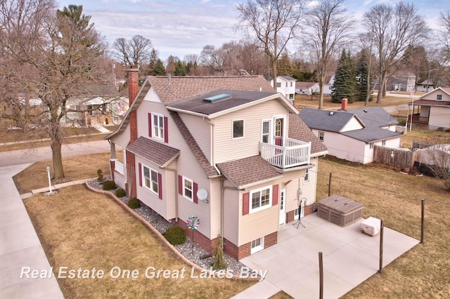 exterior space with a lawn, a residential view, roof with shingles, a balcony, and a chimney