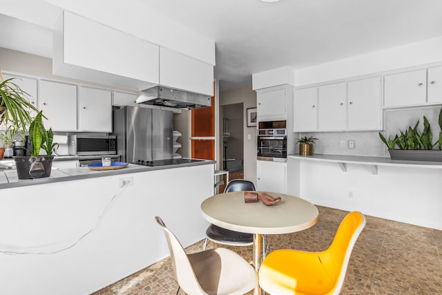 kitchen with under cabinet range hood, white cabinetry, stainless steel appliances, and light countertops