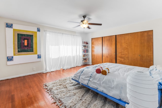 bedroom with a closet, baseboards, wood finished floors, and a ceiling fan