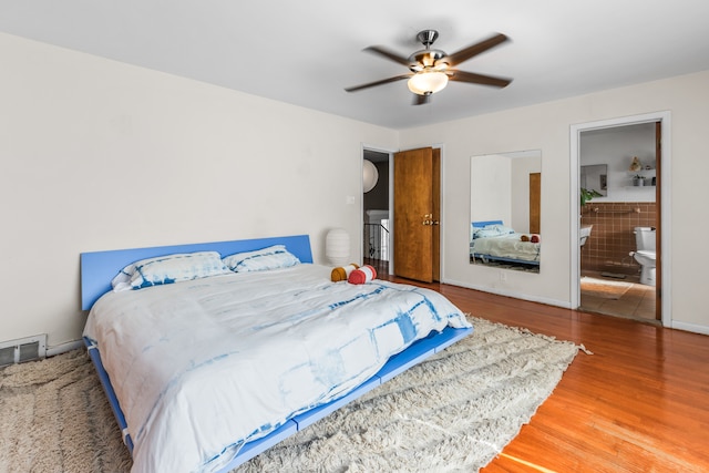 bedroom with visible vents, ensuite bathroom, wood finished floors, baseboards, and ceiling fan