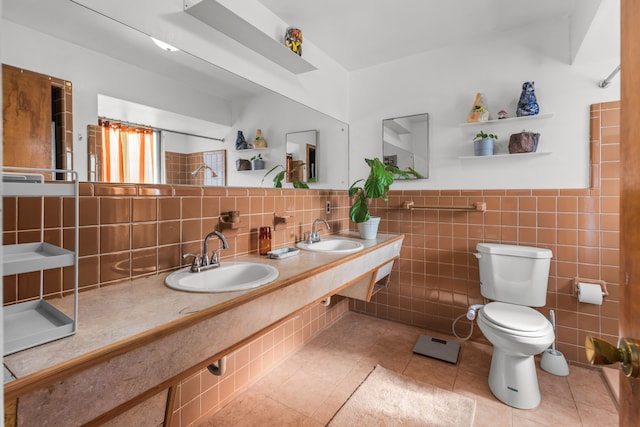 bathroom with a sink, toilet, wainscoting, and tile patterned flooring