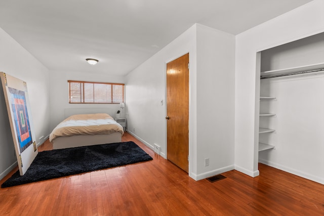 unfurnished bedroom with visible vents, baseboards, a closet, and hardwood / wood-style floors