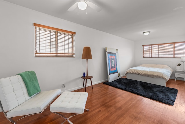 bedroom with baseboards, multiple windows, wood finished floors, and a ceiling fan